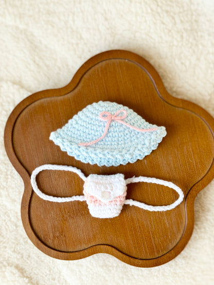 Close-up of the crochet sky-blue hat and blush-and-cream mini backpack arranged on a wooden tray.
