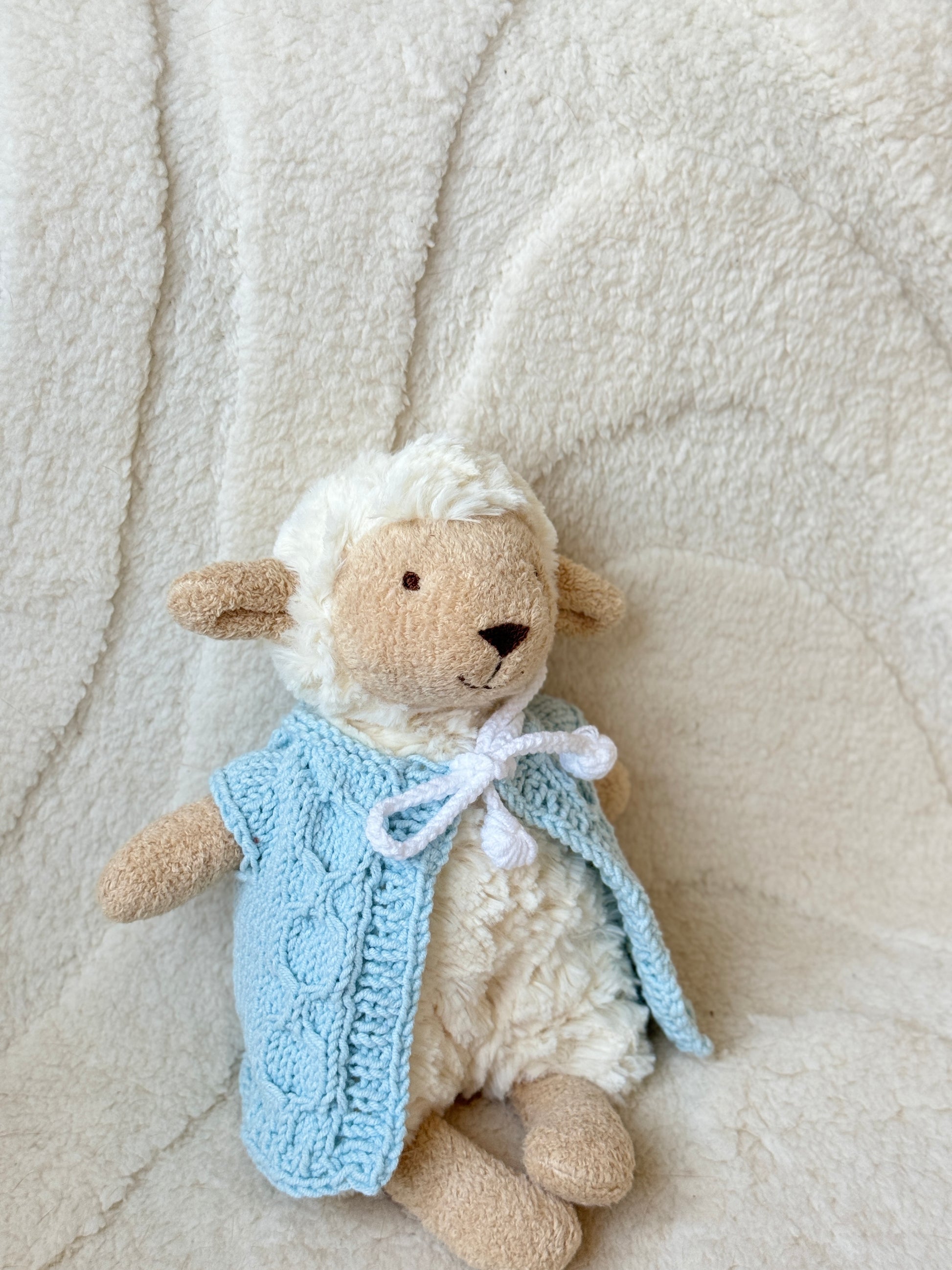 Close-up of Jellycat Lollie Lamb plush in a soft blue hand-knitted vest, showcasing the stitch pattern and fit.