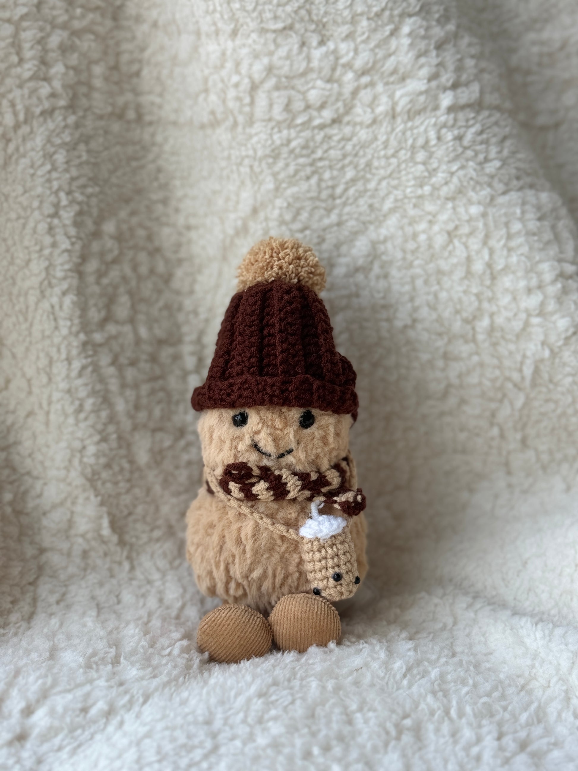Handmade crochet boba tea outfit for Jellycat Peanut — dark chocolate ribbed bobble hat, striped brown scarf, mini boba cup, front view on cream background