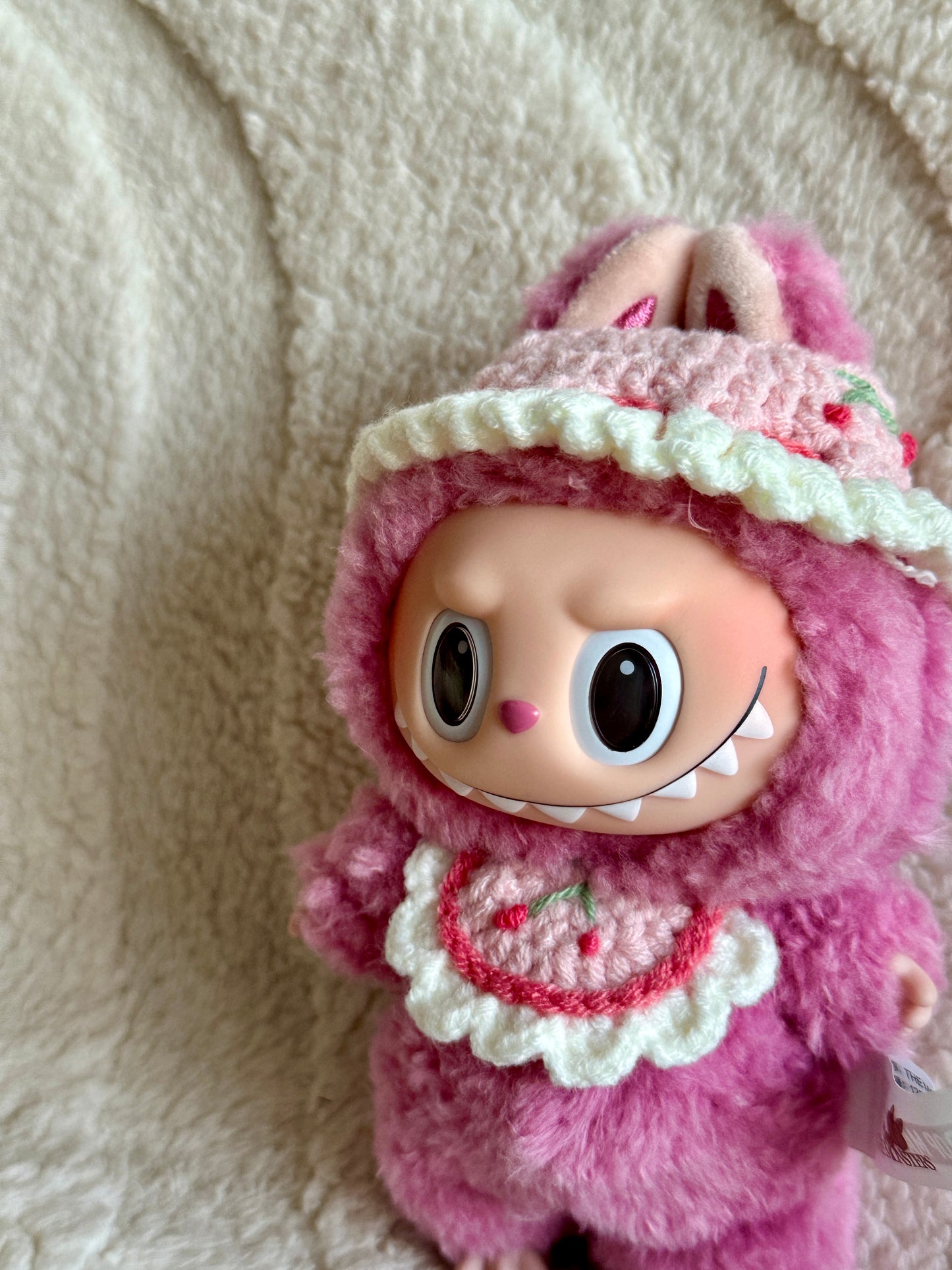 Labubu meimei smiling mischievously in a close-up shot of the crochet outfit.