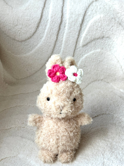 Jellycat bunny wearing colorful crochet flower clips—pink, red, blue, and white—styled on their heads.