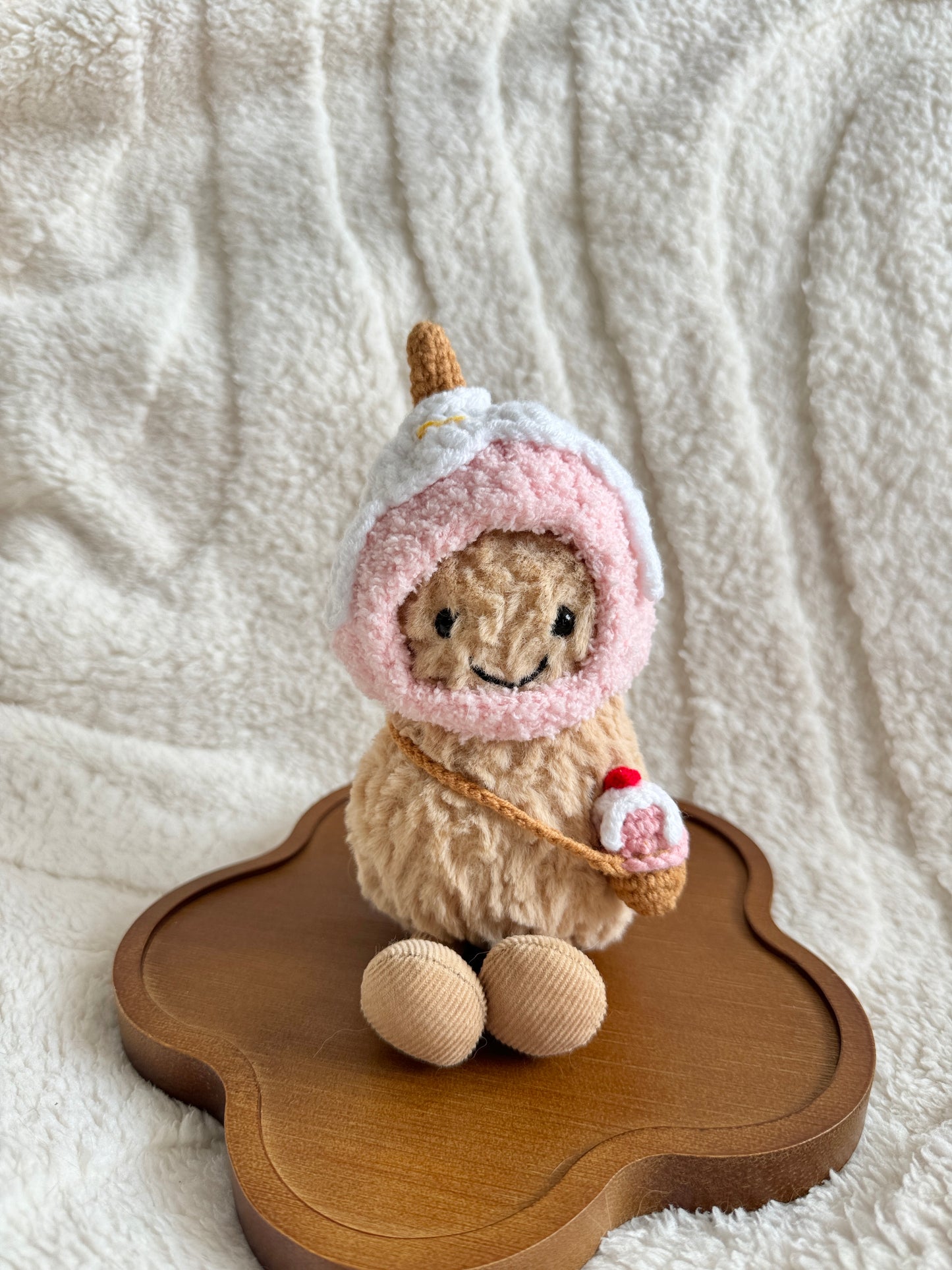 Jellycat Peanut plush wearing a handmade pink crochet ice cream hat and holding a mini crochet cone bag, front view.