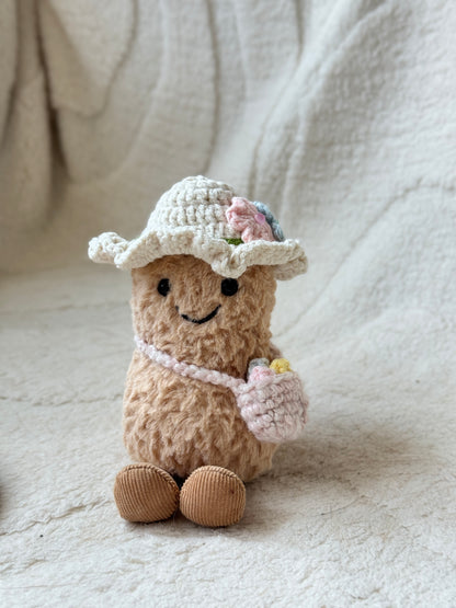 Jellycat Amuseable plush wearing cream crochet sunhat with pastel flowers and pink shoulder bag.