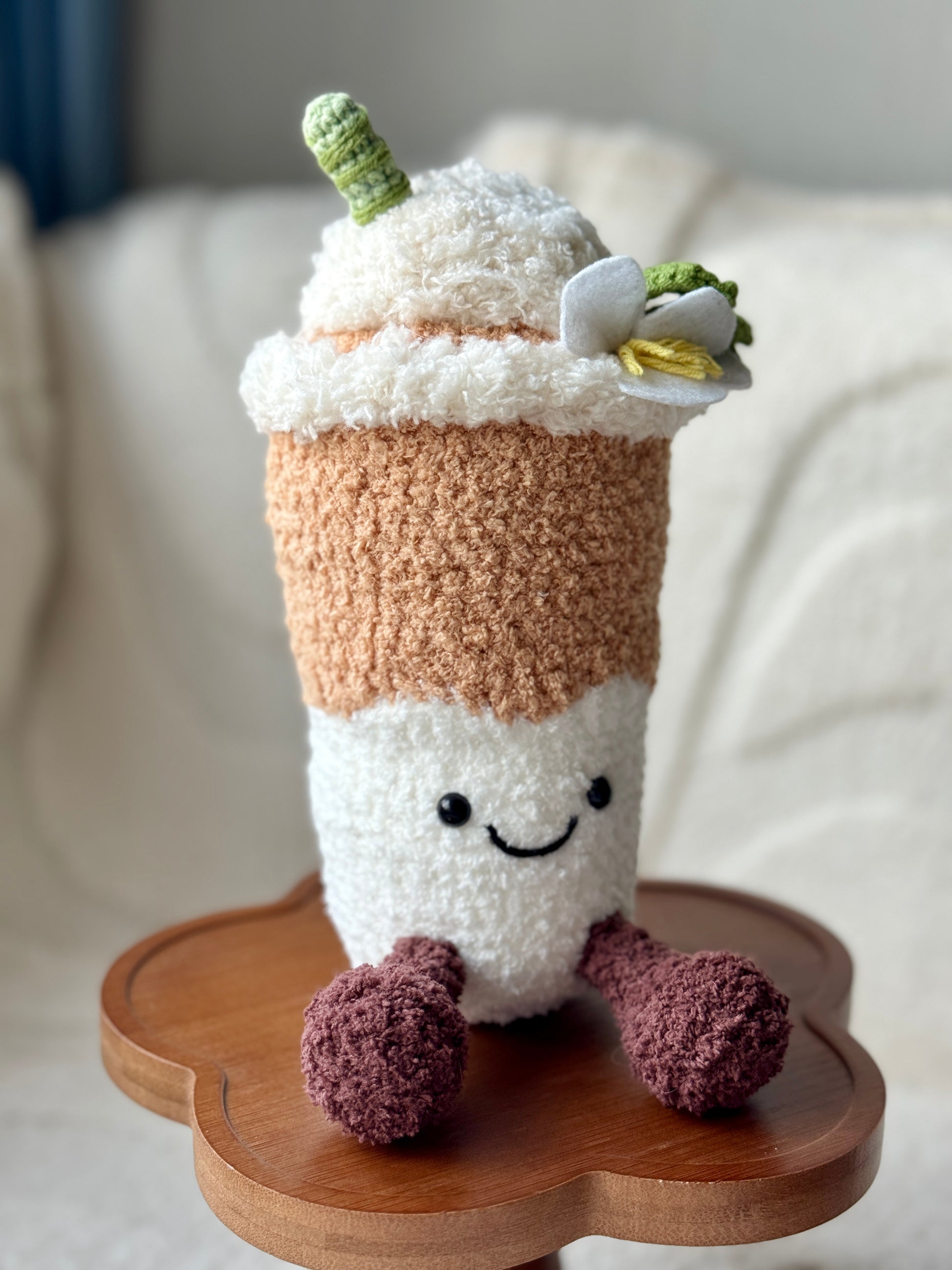Side angle of the crochet latte plush highlighting the whipped top, flower, and green straw detail.