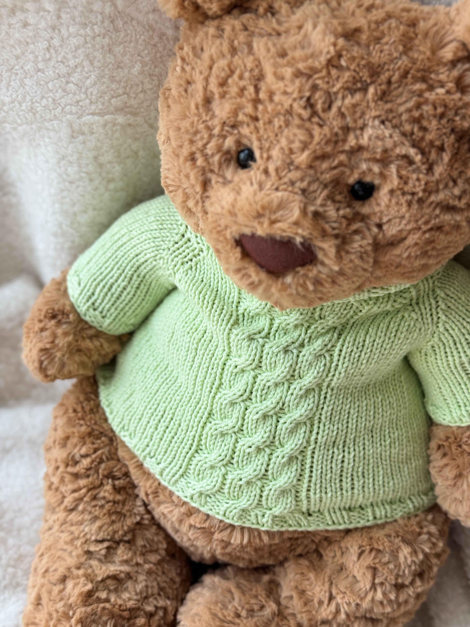 Jellycat Bartholomew Bear in a handmade green knit sweater with classic cable texture and a soft high-neck design.