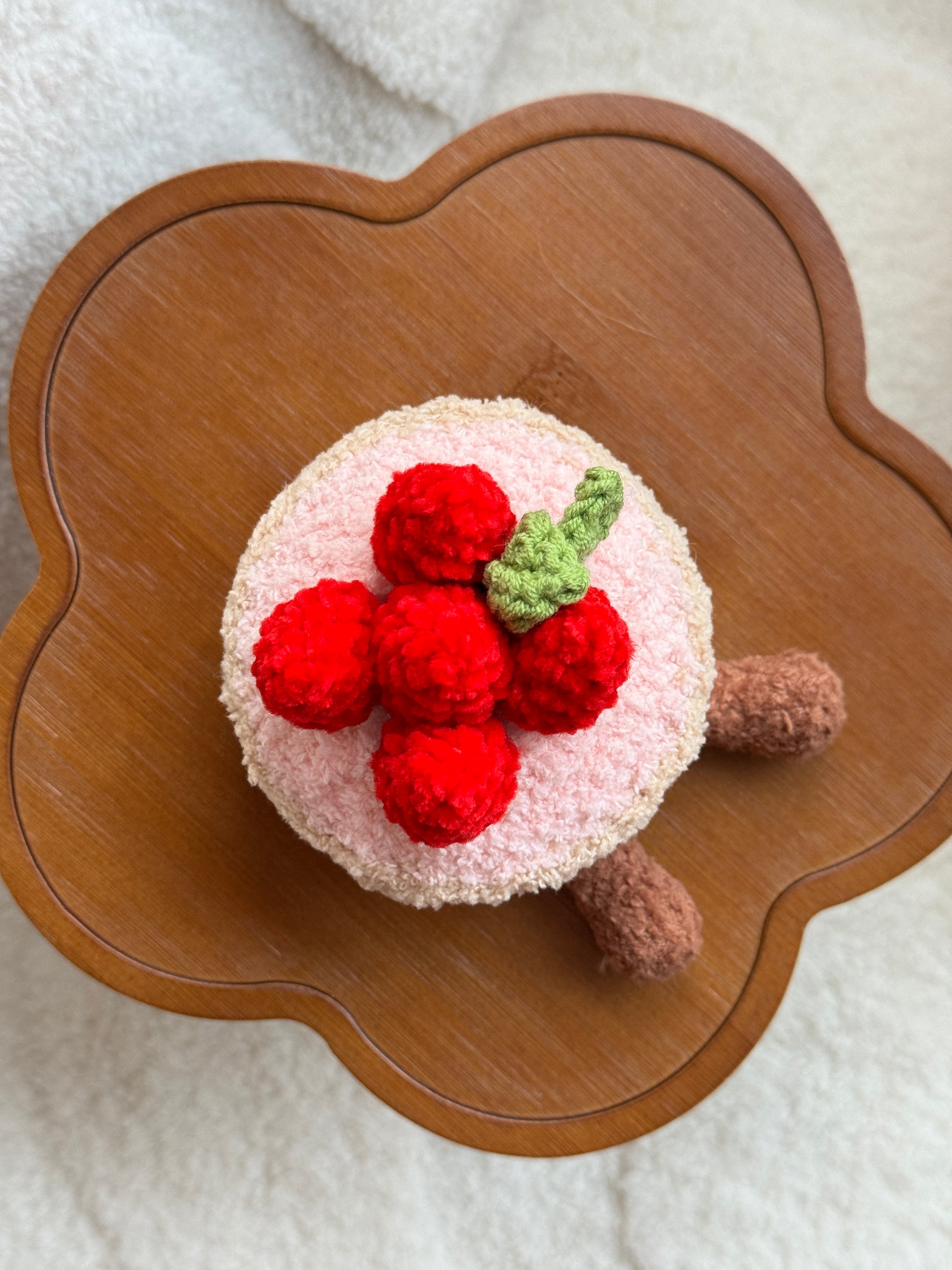 Top-down view of crochet Fleurette Tarte aux Fraises plush showing detailed strawberries and leaf on pink topping
