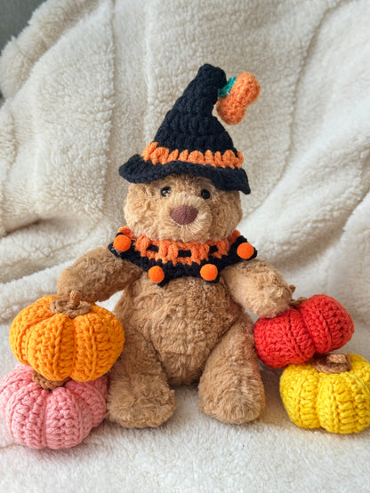 Jellycat bear in black-orange crochet pumpkin witch hat and ruffle collar for 15 cm plush, with four crochet pumpkins around.