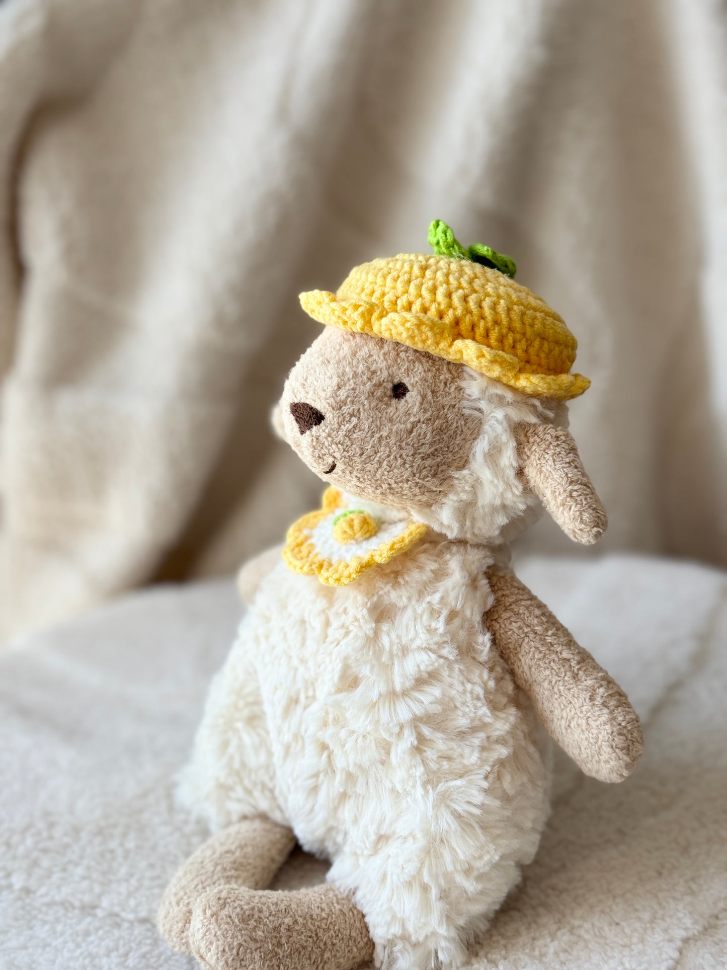 Side view of Jellycat Lollie Lamb in crochet lemon hat and bib set