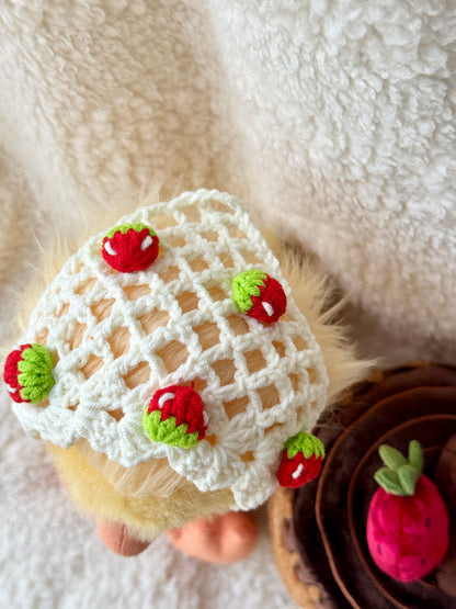 Top view of handmade crochet strawberry triangle bonnet for Jellycat Dorit Duck, featuring a cream openwork headscarf design with miniature red and green strawberry accents.