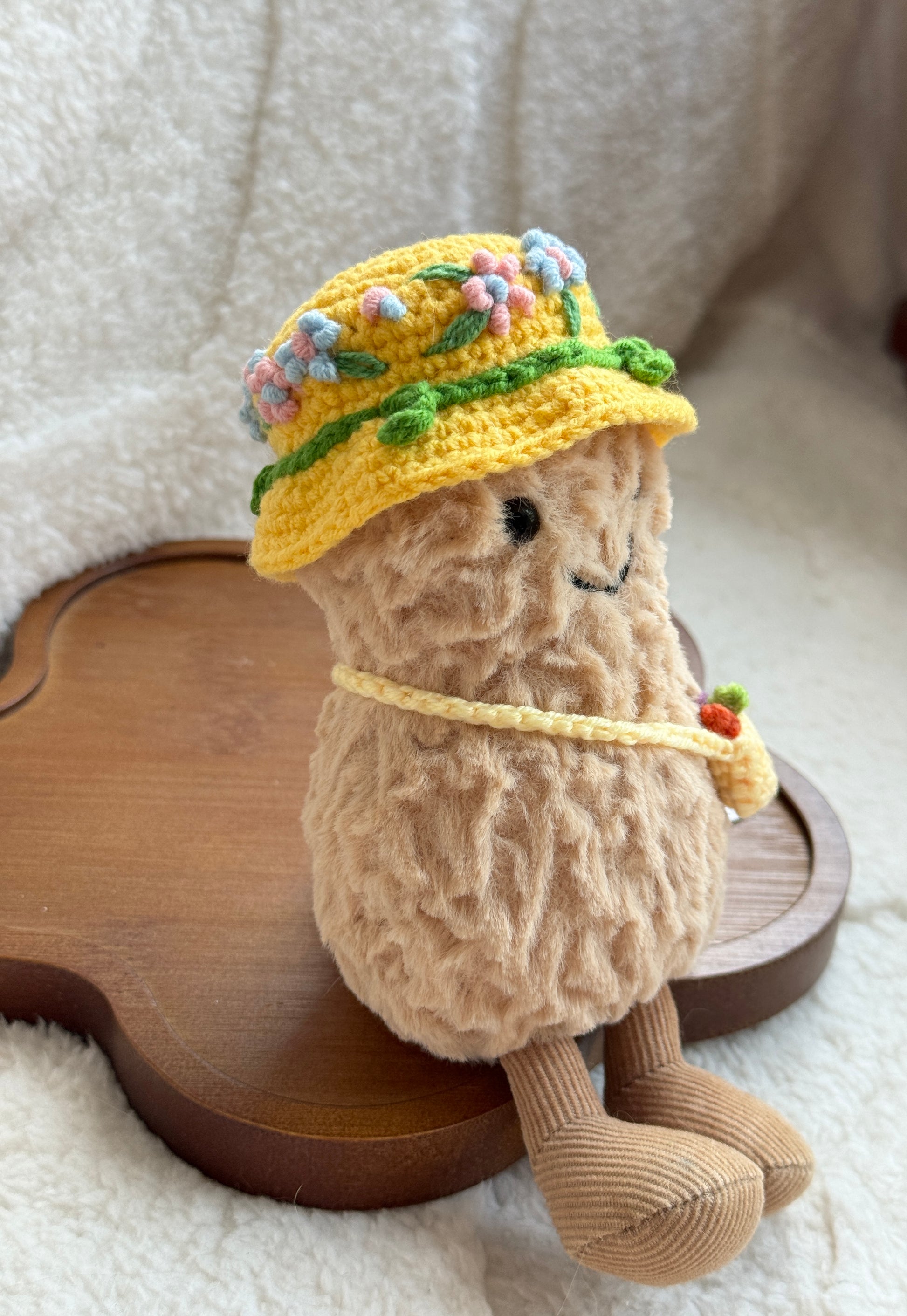 Side view of plush toy in a yellow hand-crocheted hat with embroidered flowers and matching yellow bag.
