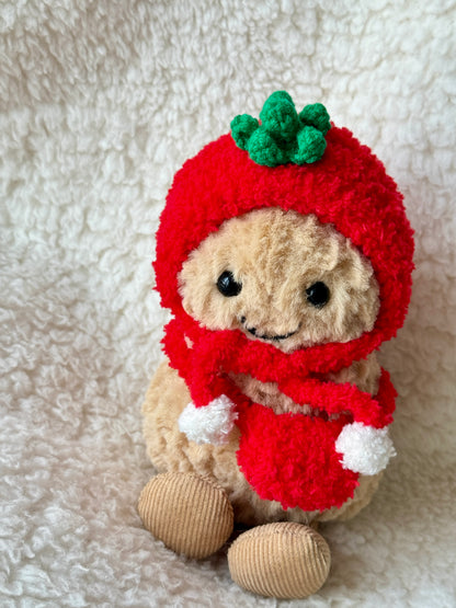 Close-up of handmade crochet tomato hat on Jellycat Peanut showing green sculpted leaf top detail and soft red chenille yarn texture