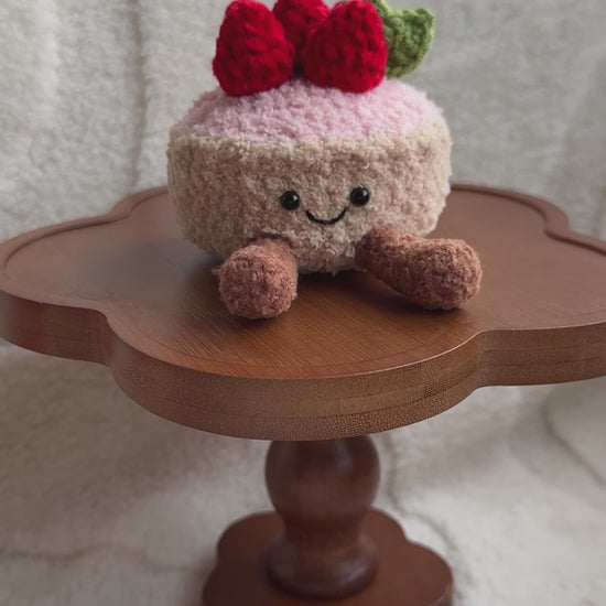 Front view of smiling crochet strawberry tart plush inspired by Jellycat Amuseables.